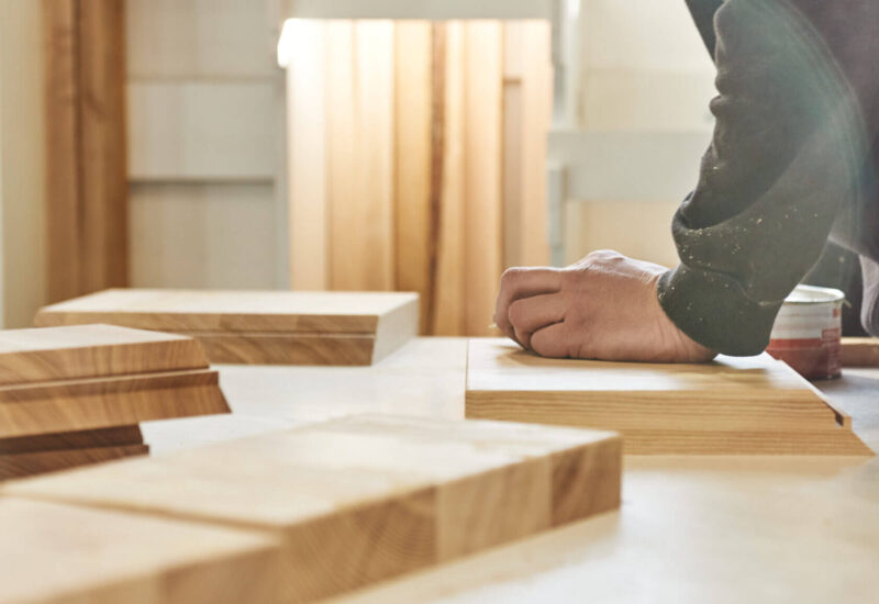 Carpenter working with wooden pieces in carpentry shop. Horizontal shot