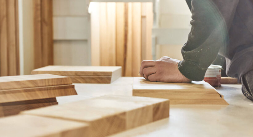 Carpenter working with wooden pieces in carpentry shop. Horizontal shot